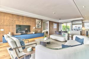 a living room with white furniture and a tv at Superior Three Bedroom Apartment in Cape Town
