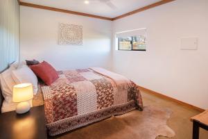 Rosa Glen Retreat - Margaret River في Rosa Glen: غرفة نوم عليها سرير ولحاف