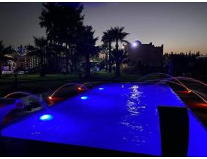 Had Abdallah RhiatPalace with 2 villas and 2 swimming pools in Sidi Abdellah Ghiat的夜间公园里一个拥有蓝色灯光的游泳池