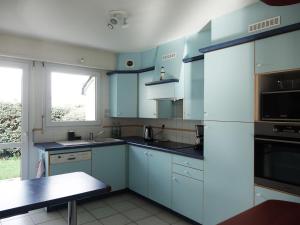 a kitchen with blue cabinets and a sink and a microwave at Maison charmante proches plages - 9 pers. - jardin, vélos, calme - Arzon - FR-1-639-22 in Arzon