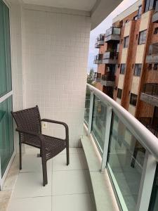 una silla sentada en el balcón de un edificio en Mandai 02 suítes apt 101 MC temporadas, en Cabo Frío