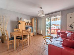 a living room with a table and a red couch at Appartement Moderne avec Balcon, Proche Centre et Plage, Piscine et Parking, Hendaye - FR-1-2-399 in Hendaye