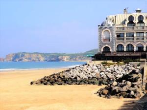a building on the beach with a pile of rocks at Appartement Moderne avec Balcon, Proche Centre et Plage, Piscine et Parking, Hendaye - FR-1-2-399 in Hendaye