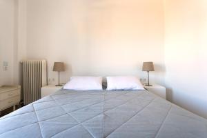 a white bedroom with a large bed with two pillows at Hotel Roumani in Spetses