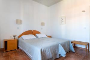 a white bedroom with a bed and a night stand at Hotel Roumani in Spetses
