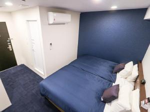 um quarto com uma cama e uma parede azul em HOTEL LiVEMAX Nigata Nagaoka Station em Nagaoka