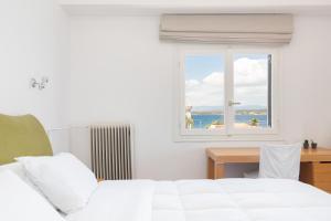 a bedroom with a white bed and a window at Hotel Roumani in Spetses