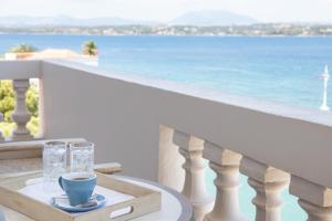 a table with glasses and a cup on a balcony with the ocean at Hotel Roumani in Spetses