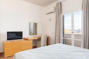 a bedroom with a bed and a desk with a television at Hotel Roumani in Spetses