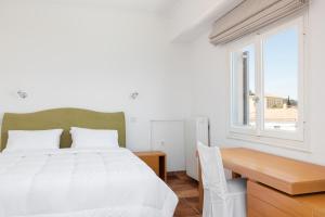 a bedroom with a bed and a desk and a window at Hotel Roumani in Spetses