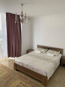 1 dormitorio con cama y lámpara de araña en коттедж Raduga West 32 en Koshkolʼ