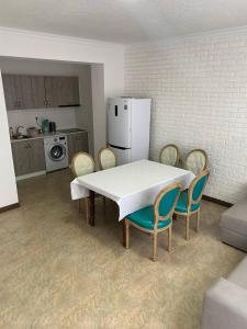 cocina con mesa, sillas y nevera en коттедж Raduga West 32 en Koshkolʼ