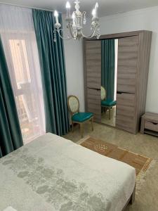 1 dormitorio con cama, espejo y lámpara de araña en коттедж Raduga West 32 en Koshkolʼ