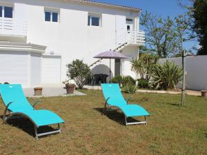 two blue chairs and an umbrella in front of a house at Maison bord de mer à la Cotinière, 3 chambres, terrasse et parking, 6 couchages - FR-1-246A-101 in Saint-Pierre-dʼOléron