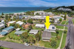 an aerial view of a suburb with a yellow arrow pointing to a house at 13 Indigo Avenue - 'Indigo Sands' - Rainbow Beach in Rainbow Beach