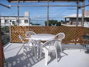 a white table and four chairs on a patio at ハイビスヤブ Hibisyabu in Nago