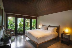 Un dormitorio con una cama grande y grandes ventanales. en Villa Puri Tupai, en Ubud