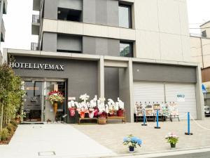 un negozio di fronte a un edificio con fiori in esposizione di HOTEL LiVEMAX Saitama-Asaka-Ekimae a Asaka