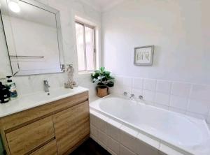 a bathroom with a tub and a sink and a mirror at Entire 4 bedroom house in Berwick, no sharing in Berwick