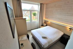 Una habitación de hotel con una cama y una ventana. en Hotel Cecil, en De Panne