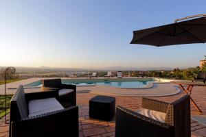 a swimming pool with chairs and an umbrella at Tenuta Lisetta in Monterotondo