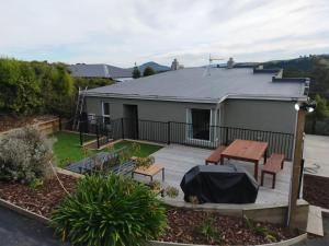 a house with a deck with a table and benches at Relax in Kenmure in Dunedin