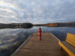a little girl standing on a dock on a lake at Villa Joutsen with jacuzzi in Vuoriniemi