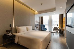 a hotel room with a large white bed and a desk at Atour Hotel Yancheng ETDZ in Yancheng