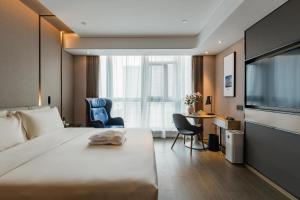 een hotelkamer met een groot bed en een bureau bij Atour Hotel Suzhou North High-Speed Railway Station in Suzhou