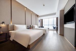a hotel room with two beds and a flat screen tv at Atour Hotel Changde Laoximen in Changde