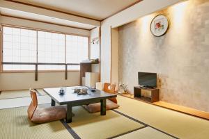 uma sala de estar com uma mesa e cadeiras e uma televisão em 京都駅前ひふみ旅館（HifumiRyokan Kyoto station) em Quioto
