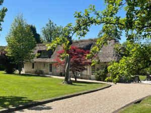 a house with a thatched roof and a pathway at LES 2 CHAUMIÈRES Piscine & Spa in Ablon