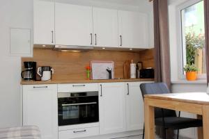 a white kitchen with white cabinets and a table at Lieblingshaus Eddie in Prerow
