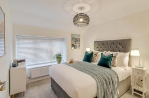 a bedroom with a large bed with blue pillows at Spacious 6-Bed Home, Near The Norfolk Broads in Clippesby