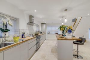 a kitchen with white cabinets and a counter with flowers on it at Spacious 6-Bed Home, Near The Norfolk Broads in Clippesby +41 photos