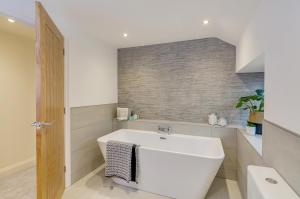 a bathroom with a white tub and a sink at Spacious 6-Bed Home, Near The Norfolk Broads in Clippesby