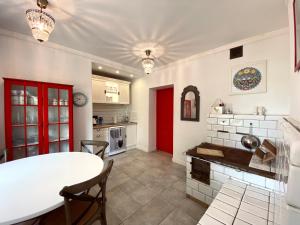 a kitchen with a white table and a red door at Dom Ogrodnika in Biała Olecka