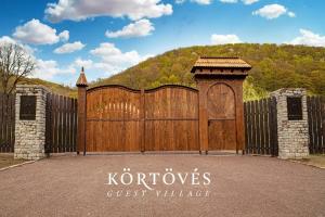 um grande portão de madeira com um sinal que lê a aldeia de hóspedes dos korros em Körtövés Guest Village em Vîrghiş