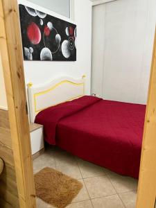a bedroom with a red bed and a painting on the wall at Baglio Cracchiolo da Tuzzo - Casa Il Limone in San Vito lo Capo