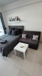 ein Wohnzimmer mit schwarzem Sofa und weißem Tisch in der Unterkunft Antigona Nikiti in Nikiti