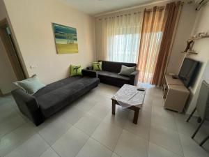 a living room with a couch and a tv at Miloen Residence Gjiri I Lalzit in Draç