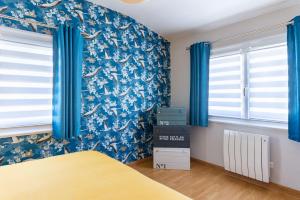 Schlafzimmer mit blauen Wänden und blauen Vorhängen in der Unterkunft Cajem in Étretat