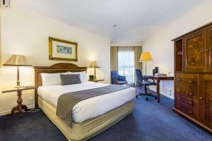 a hotel room with a bed and a desk at Quality Hotel Canterbury International in Forest Hill