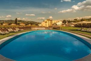 Hotel Mulino di Firenze - WorldHotels Crafted في فلورنسا: حمام سباحة ازرق كبير مع منزل في الخلفية