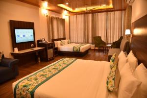 a hotel room with a bed and a television at Mastiff Hotel, Gopalpur in Pālampur