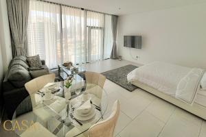 a living room with a glass table and a bed at Stunning STD Flat in DT, with Burj Khalifa view . in Dubai