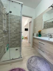 een badkamer met een glazen douche en een wastafel bij La Casa dei Nonni in Avigliano
