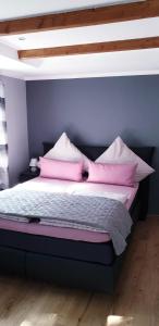 een slaapkamer met een bed met roze kussens erop bij Ferienwohnung Anna in Marienhafe