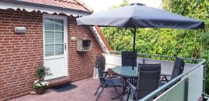 een patio met een tafel en stoelen en een parasol bij Ferienwohnung Anna in Marienhafe