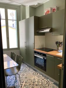 kuchnia z zielonymi szafkami i stołem z krzesłami w obiekcie Suite Alsace Lorraine FSHH w Nicei